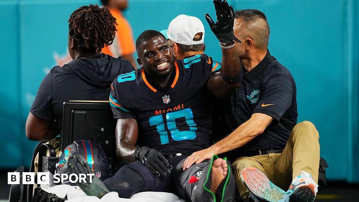 Tyreek Hill smiles and waves as he sits on a buggy