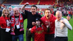 (L-R) Actors and Wrexham owners Rob McElhenney and Ryan Reynolds with former Wrexham footballer Mickey Thomas and Executive Director, Kaleen Allyn with her dad, Manager and Chief Investment Officer of the Allyn's Family Office, Eric Allyn, celebrate being promoted to the Championship League One - Wrexham v Charlton Athletic - SToK Racecourse, Wrexham, U.K., April 26, 2025. (Reuters Photo)