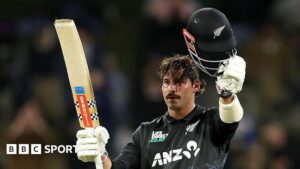 Tim Robinson raises his bat and helmet after reaching his century